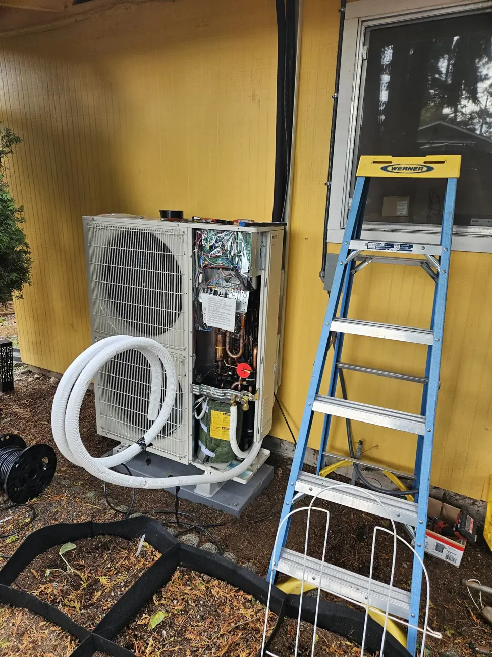 Outdoor heat-pump unit with its service cover open during installation work