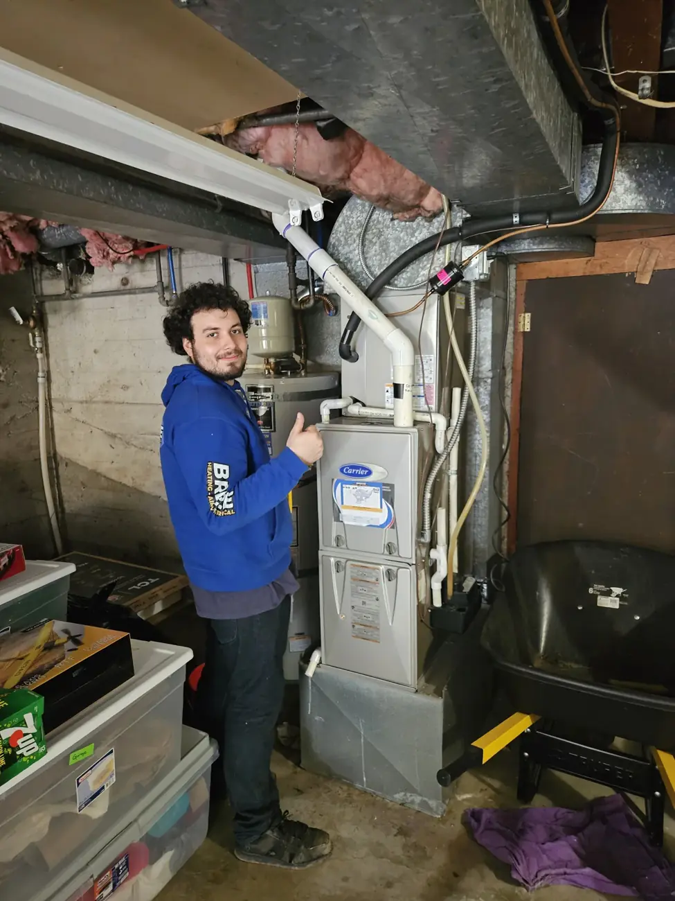 A Breeze technician giving a thumbs-up beside a residential furnace