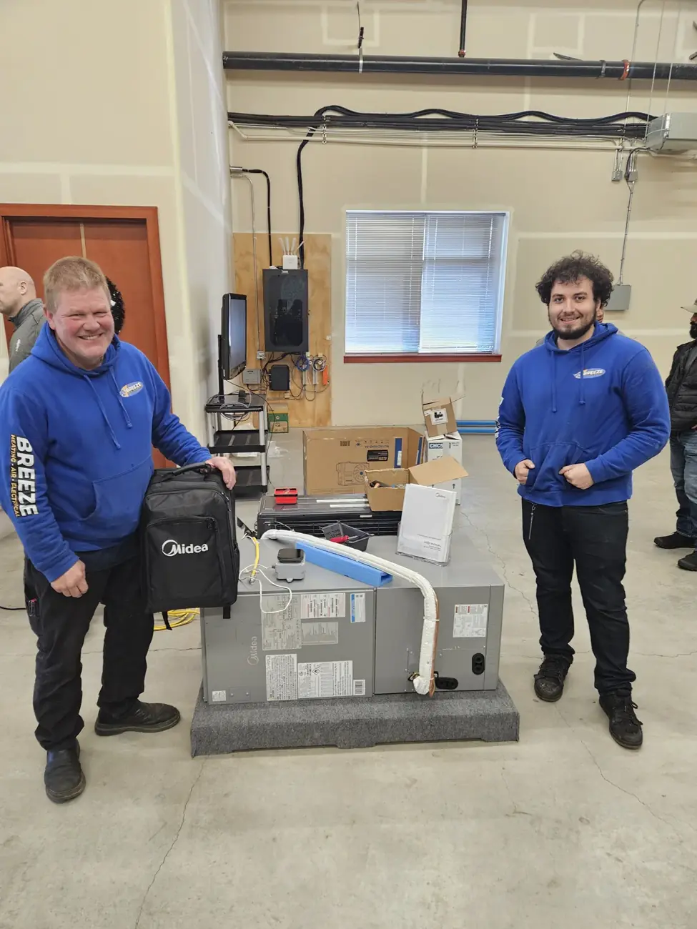 Two Breeze team members beside HVAC equipment at a training session