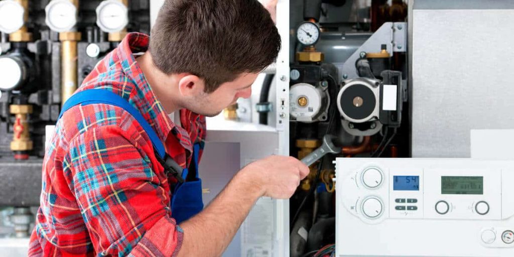 Technician performing maintenance on a heating system, ensuring optimal performance for home heating installation and replacement services in Kent, WA.
