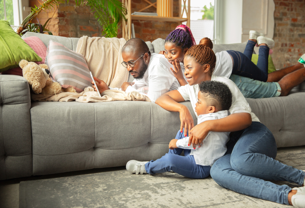Family on couch using tablet, enjoying indoor comfort. Consider heating repair in Seattle, WA to ensure a cozy home environment year-round.