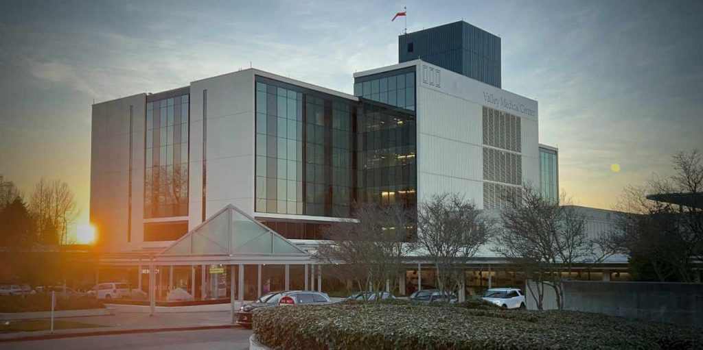 Valley Medical Center in Kent, WA at sunrise. Modern facility with a helipad and glass facade, symbolizing healthcare excellence near Seattle, WA.