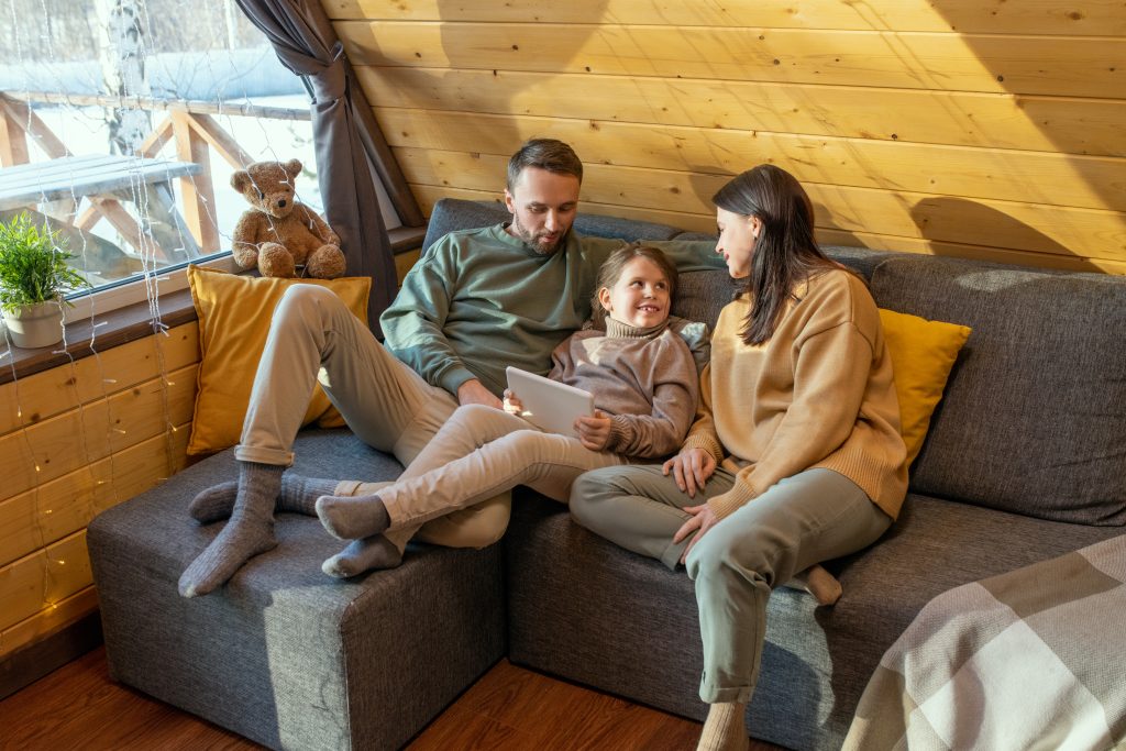 Family enjoys time together in Kent, WA, on a cozy couch. A daughter holds a tablet while parents look on, creating a warm family scene.