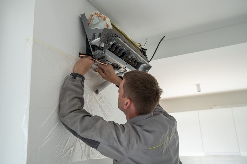 Technician repairing ductless mini-split system in residential setting, ensuring efficient heating and cooling for Kent homeowners.