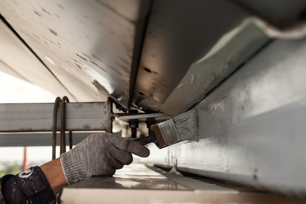 Aeroseal Service: A worker in Seattle, WA, applies sealant to an HVAC duct with a brush, ensuring air duct sealing and energy efficiency.