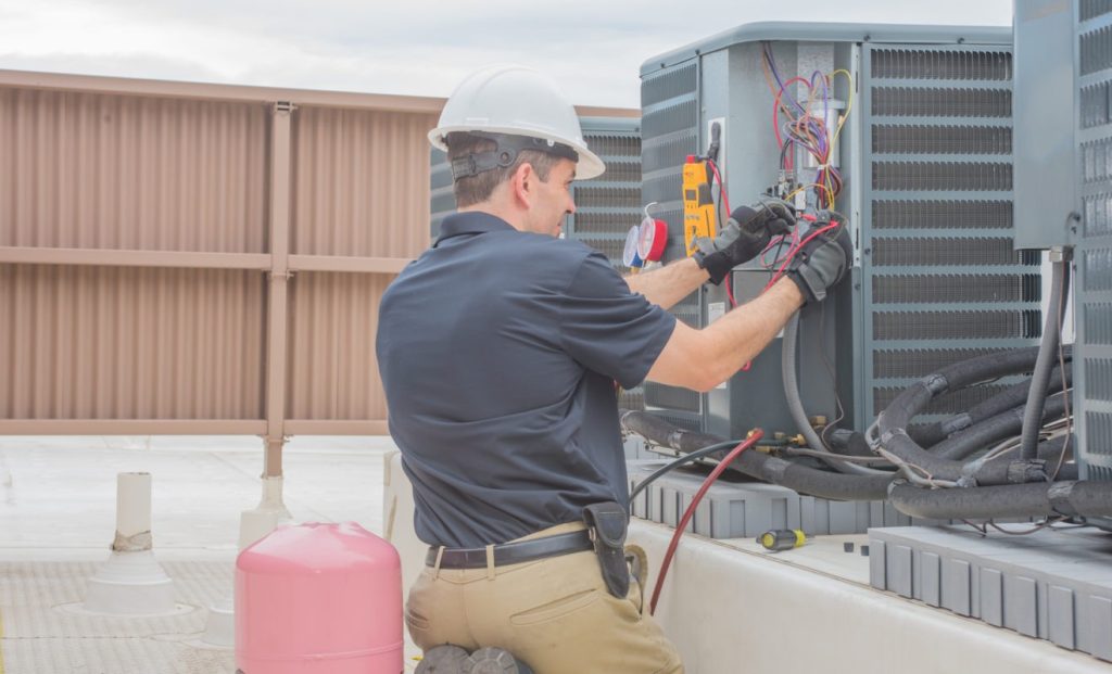 HVAC technician performing maintenance on outdoor air conditioning unit, emphasizing reliable HVAC services in Bellevue, WA.