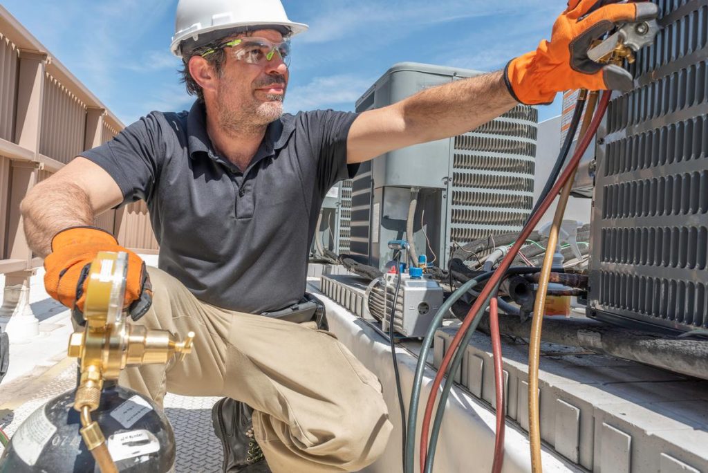 North Bend Location: HVAC technician in safety gear services rooftop AC units. Repair and maintenance for peak performance in North Bend.
