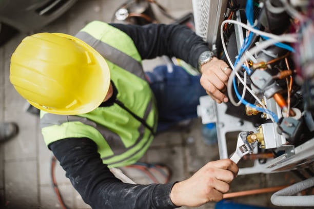 HVAC technician in safety gear repairing equipment, showcasing expertise in heating and cooling services for Renton, WA homeowners.