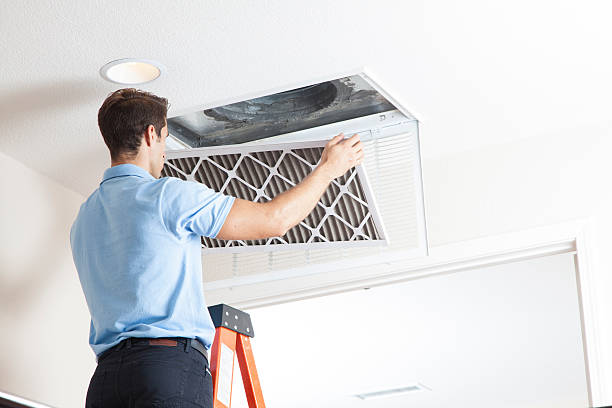 Technician installing a high-efficiency air filter in a ceiling vent, emphasizing professional air filter services for improved indoor air quality in Kent homes.