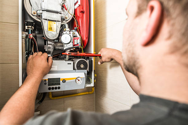 Technician performing maintenance on a heating system, inspecting components and ensuring safe operation for reliable home heating in Kent, WA.
