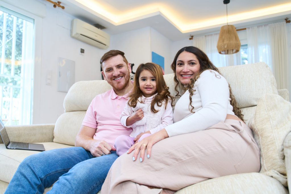 Happy family of three smiling on a couch in Federal Way. Location Page relevance for local SEO. Seattle, WA area representation.